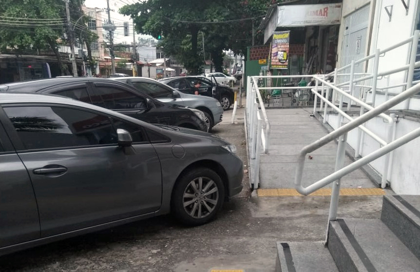 Carros estacionam irregularmente na calçada da Estrada do Dendê, em frente a agência do Bradesco no Tauá