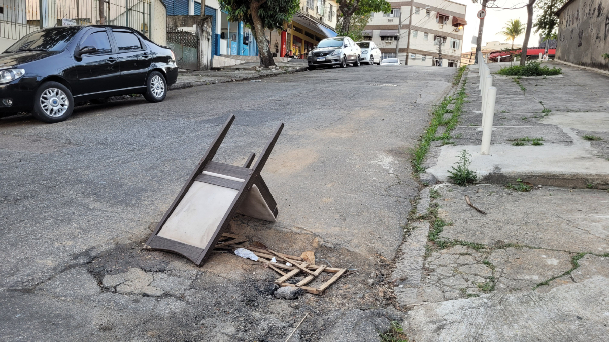 Buraco na Rua Crundiúba sinalizado com uma cadeira