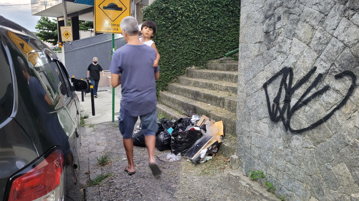 Pedestres caminham em meio ao lixo na Rua Colina