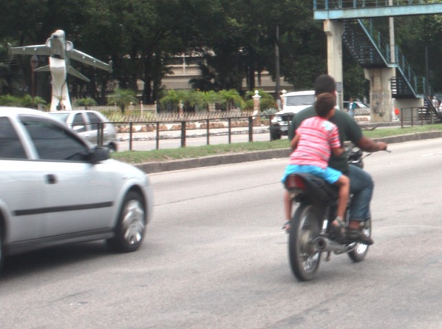 Na tarde do sábado (19), o motoqueiro e o carona, que parece uma criança, sem capacetes, se arriscam na Estrada do Galeão na moto sem placa. Uma patrulha da PM os ultrapassou e nada fez