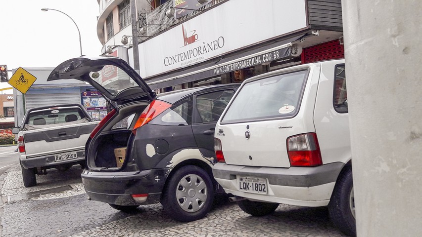 Prejudicando os pedestres e abrindo buracos nas calçadas, veículos comuns e de carga, usam o calçadão como estacionamento e para descarregar mercadorias diariamente junto a passarela na Portuguesa