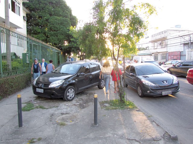 Nas calçadas da Estrada do Dendê, o espaço para os pedestres é tomado por carros estacionados
